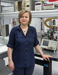 Dr. Camelia Miron im INP-Labor neben Messtechnik und Versuchsaufbau.