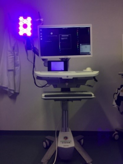 Mobile Diagnostikeinheit mit Monitor und hyperspektraler Kamera, die violettes Fluoreszenzlicht zur Erkennung von Bakterien aussendet.