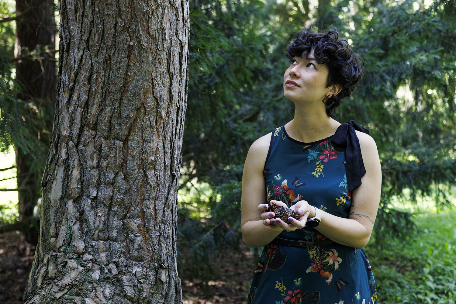 Dr. Thalita Nishime mit Baumsamen an einem Baum, im Kontext ihrer Forschung zur Verbesserung der Keimung