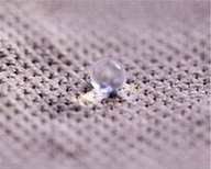 Wassertropfen perlt auf einer textilen Oberfläche ab und veranschaulicht eine hydrophobe Oberflächenmodifizierung.