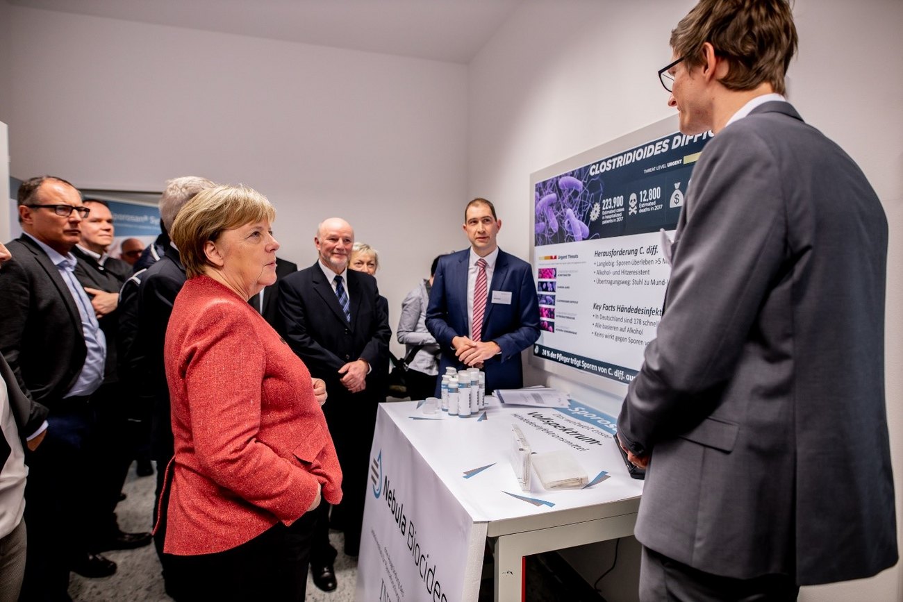 Angela Merkel informiert sich bei einer Projektpräsentation zu Sporosan über hygienische Herausforderungen und Lösungsansätze.