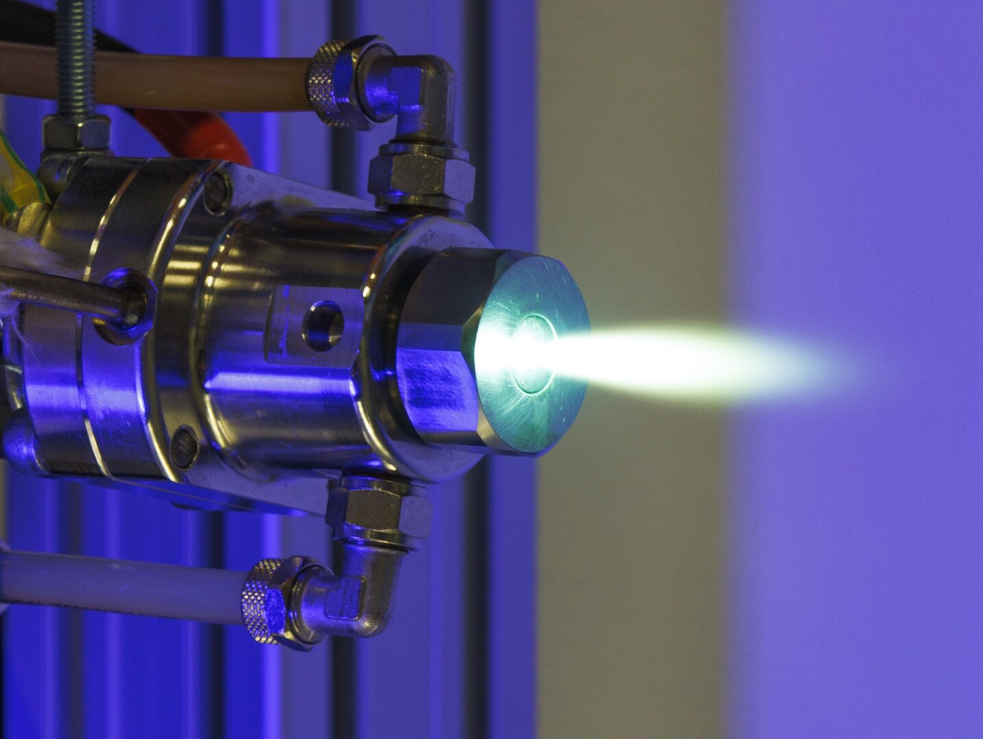 Thermisches Plasma tritt als heller Strahl aus einer metallischen Düse aus, Teil einer Anlage zur materialtechnischen Verarbeitung.