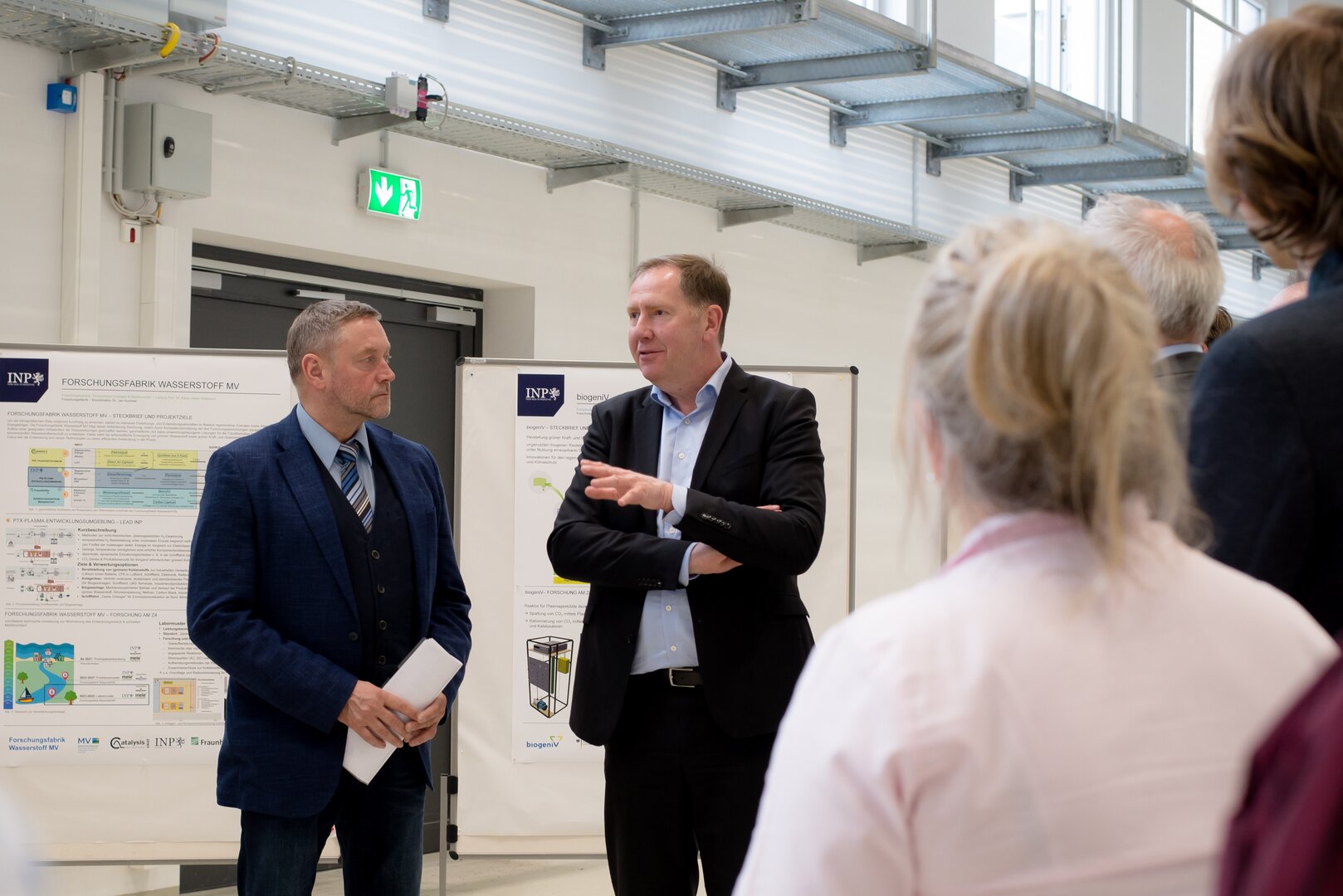 Heiko Miraß (2. v. l.) im Gespräch mit Klaus-Dieter Weltmann beim Informationsbesuch im INP, vor Forschungsplakaten in einem Laborbereich.