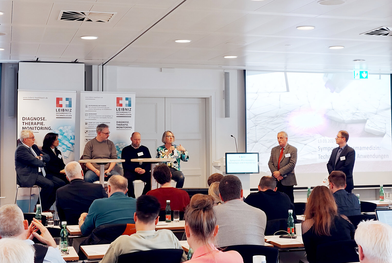 Podiumsdiskussion mit mehreren Fachpersonen vor Publikum bei einer Fachveranstaltung zur Plasmamedizin in einem Konferenzraum.